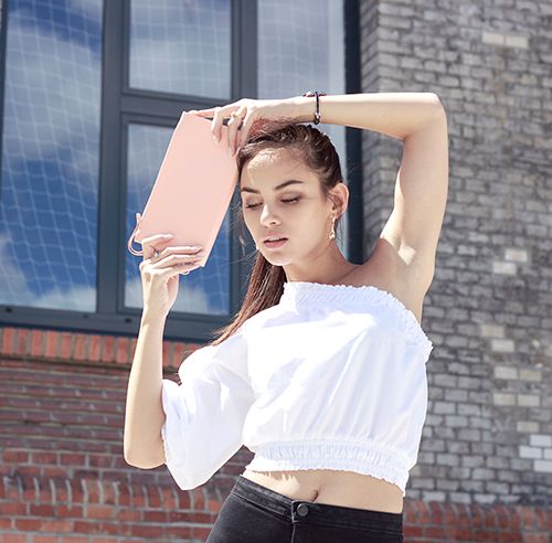 Hnedovlasá modelka s elegantnou koženou listovou kabelkou a drevenou listovou kabelkou