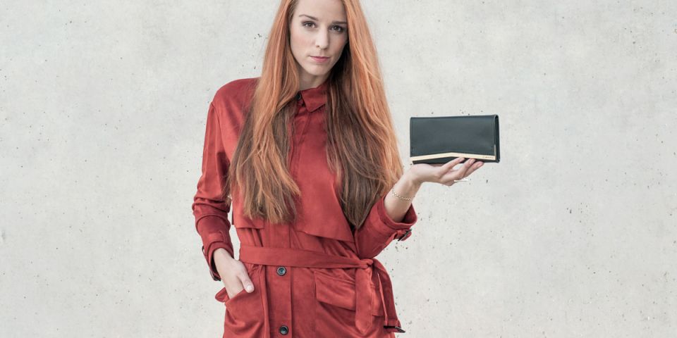 BeWooden - Žena s ryšavými vlasmi v oranžovom kabátiku drží koženú peňaženku Liti Woman Wallet